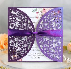 Detailed laser-cut purple wedding invitation card with elegant silk ribbon bow and floral motif