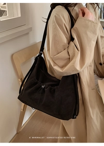 Detail of black suede tote bag with drawstring texture shown on a female model