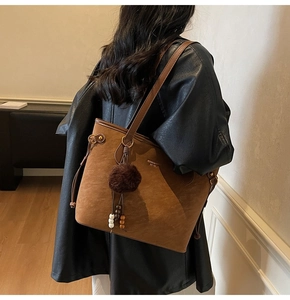 Vue détaillée d'un grand sac cabas marron vintage avec boule en peluche et perles