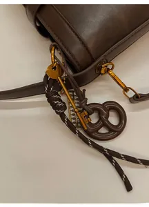 Detailed shot of dark brown leather bucket bag with vintage gold hardware and charms