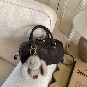 Detailed view of brown matte leather bowling bag with cute plush rabbit charm