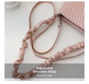 Detail view of the pink quilted handbag featuring an adjustable ruched shoulder strap