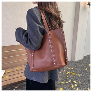 Detailed view of silver rivets on large brown litchi pattern leather tote bag