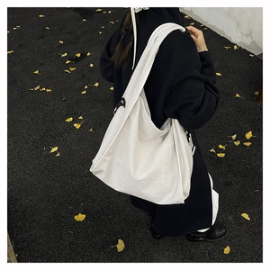 Outdoor shot of cream-colored canvas hobo bag showing large capacity and soft silhouette