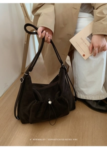 Detail of dark suede tote bag with drawstring pocket and adjustable strap on a model