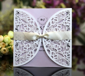 Detail of laser-cut ivory wedding invitation with purple insert and beige silk bow