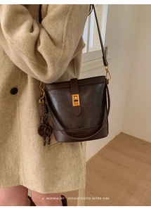 Detail of retro dark brown leather bucket bag with metal buckle and pretzel charm