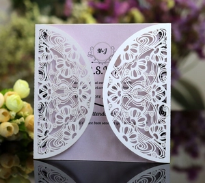 Detail of laser-cut wedding invitation with white floral shell and purple insert