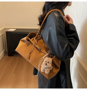 Caramel brown leather tote bag with a cute plush puppy charm shown on model