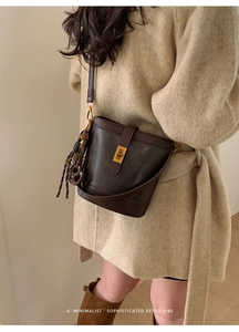 Detail of dark brown retro bucket bag featuring gold metal lock and leather texture