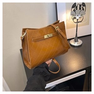 Close-up of brown quilted shoulder bag with shiny leather and gold square metal clasp