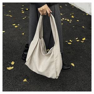 Close-up of off-white oversized canvas tote bag held by a model on autumn street scenery