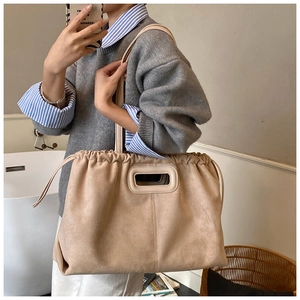 Détail du grand sac cabas en daim beige avec cordon de serrage et poignées découpées