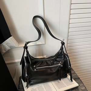 Macro detail of black faux leather shoulder bag with silver zippers and rivet hardware
