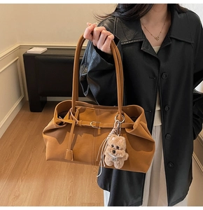 Close-up of caramel faux leather tote with pleated edges and plush teddy bear charm