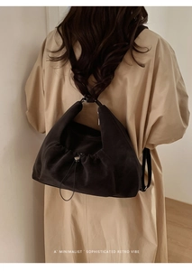 Detailed close-up of a minimalist black tote bag featuring drawstring and metal buckle closure