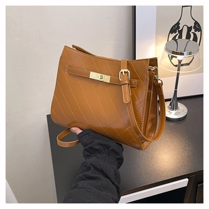 Detail of brown quilted faux leather underarm bag with gold metal lock and belt strap