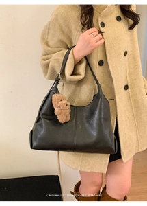 Detail of minimalist black hobo bag with a cute brown teddy bear plush charm