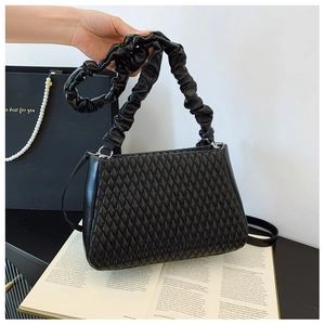 Detail of black quilted shoulder bag with unique ruffled cloud handle and leather texture