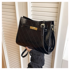 Detail of black quilted leather shoulder bag with golden clasp and glossy finish