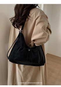 Minimalist black retro hobo bag shown on a model's shoulder for size perspective