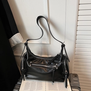 Detail of black multi-pocket shoulder bag featuring silver rivets and adjustable strap