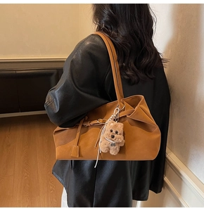 Detail of large brown suede tote bag with a cute plush bear pendant accessory