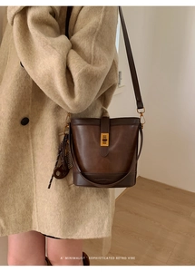 Detail of vintage dark brown bucket bag with gold twist lock and round leather charm