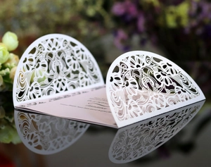 Macro detail of laser-cut ivory floral wedding invitation with elegant hollow patterns