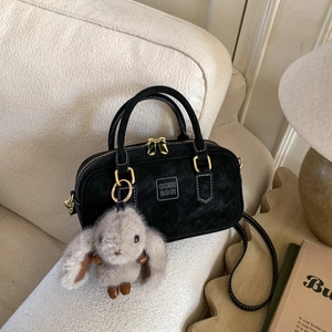 Close-up of black matte bowling bag with golden zipper and grey plush rabbit charm