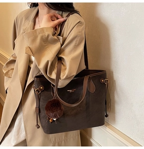 Détail d'un sac cabas vintage marron foncé avec pendentif en peluche et logo imprimé