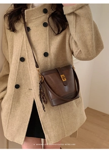 Detail of retro dark brown leather bucket bag with gold lock and silk scarf accent