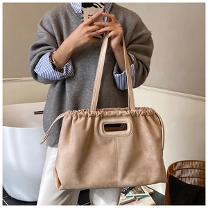 Détail du grand sac cabas en daim beige avec fermeture à cordon et poignée rectangulaire