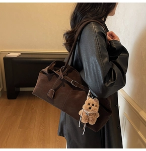 Detail of dark brown suede tote bag featuring a leather tie and cute plush dog charm