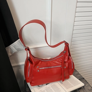 Detail view of red PU leather shoulder bag with silver hardware on a black suitcase