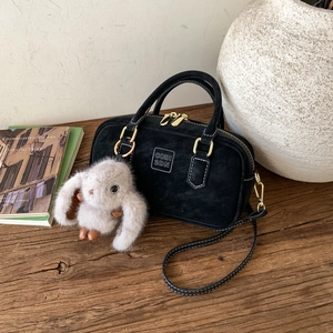 Detail of black suede pillow bag with gold zippers and a cute plush bunny charm