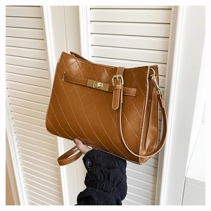 Detail of caramel quilted leather shoulder bag with gold hardware and turn-lock closure