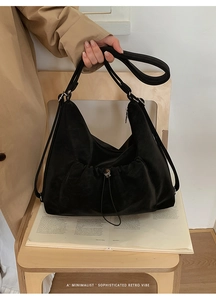 Detail of black vintage hobo bag showing pleated drawstring pocket and matte texture