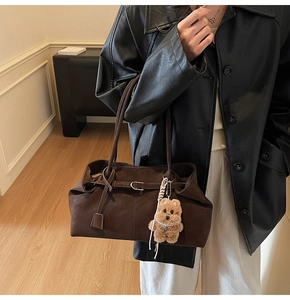 Detail of coffee suede tote bag featuring adjustable straps and plush bear charm