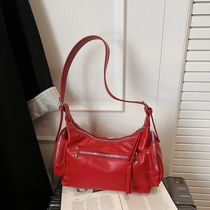 Detail of red punk-style faux leather handbag with silver zippers and rivet hardware