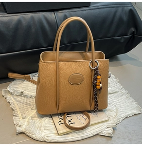 Detail of brown litchi pattern leather bucket bag with wooden bead tassel and silver hardware