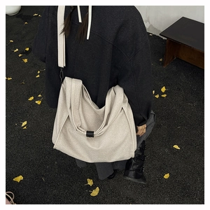 Close-up of minimalist canvas tote bag with wide strap and black buckle on autumn leaves