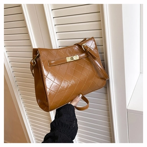 Detail of brown quilted leather handbag with diamond stitching and gold turn-lock closure