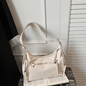 Detail of off-white shoulder bag with functional zippers and adjustable strap on luggage