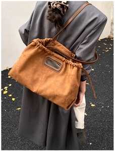 Détail d'un sac cabas en daim marron avec cordon de serrage et poignée découpée