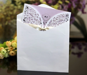 Detail of laser-cut wedding invitation with ivory lace design and beige satin ribbon bow