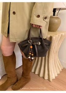 Detail of dark brown matte tote bag featuring stylish beaded charms and leather strap decor