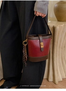 Detail of vintage bicolor bucket bag with metal buckle and woven knot charm accent