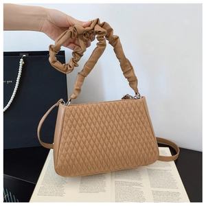Detail of caramel quilted shoulder bag featuring a scrunchie strap and diamond stitching