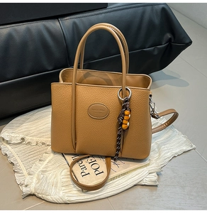 Detailed macro view of brown lychee-textured leather handbag with wooden bead charms